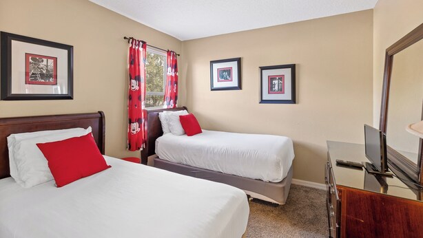 A hotel room with two beds, a television, and framed pictures on the wall. - 7 Bedroom Villa Near Disney World – Pool & Spa, Kissimmee (Kissimmee)
