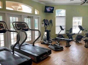 Ein Fitnessstudio mit Laufbändern, Crosstrainern und Fahrrädern.
