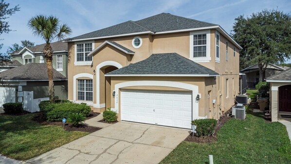 A two-story house with a garage, a driveway, and a well-maintained lawn. - 7 Bedroom Villa Near Disney World – Pool & Spa, Kissimmee (Kissimmee)