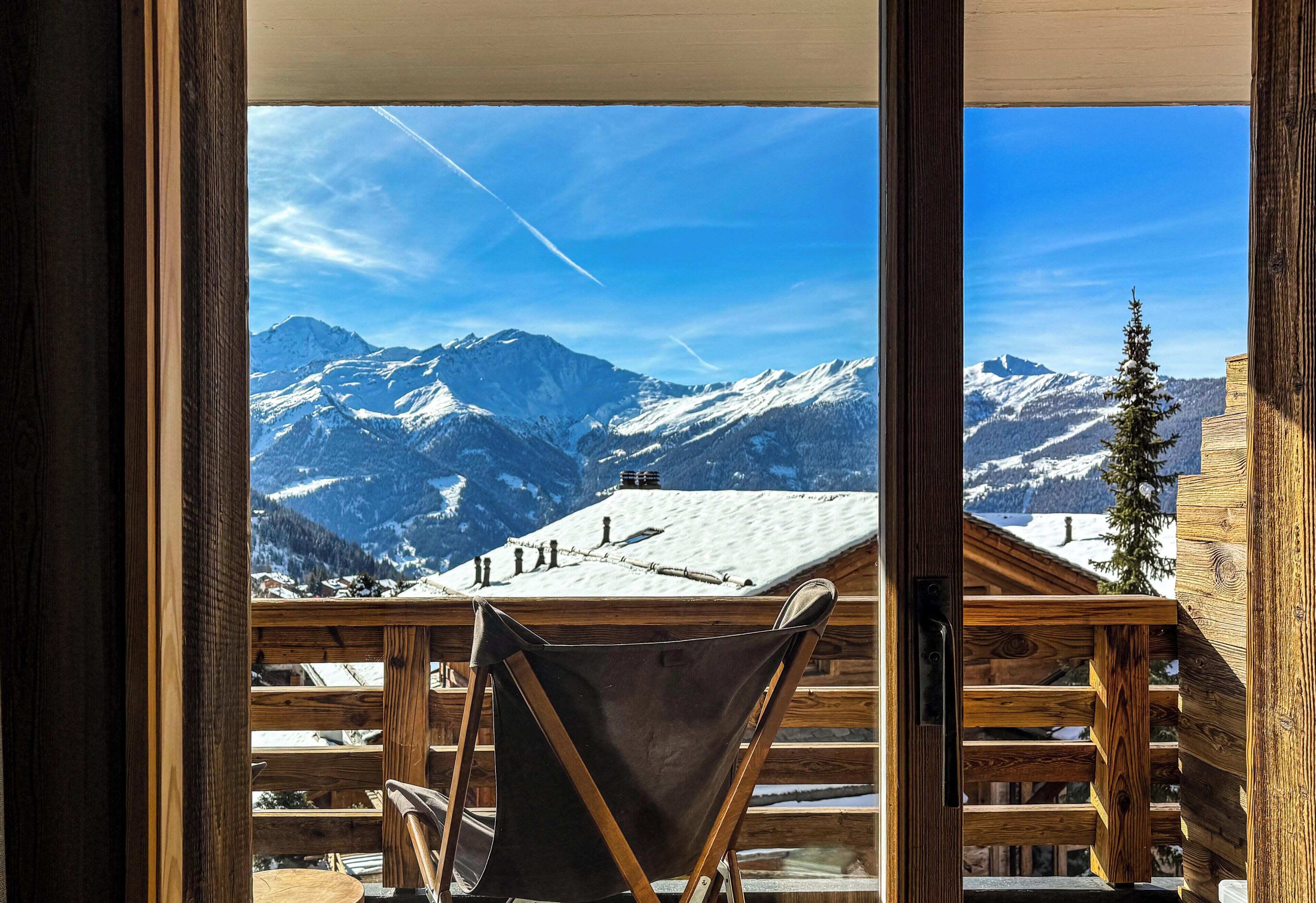 A wooden cabin with a view of snow-covered mountains.