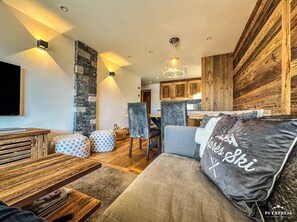 Una sala de estar moderna con un sofá, otomanas, una mesa de centro de madera y una pared de acento de piedra.