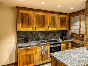 Una cocina con gabinetes de madera, encimeras de granito, cafetera y horno.