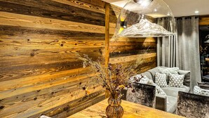 Un intérieur moderne avec un mur en bois, un luminaire suspendu et un coin repas comprenant une table et des chaises.