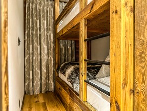 Ein Stockbett mit Holzrahmen und einem Fenster.