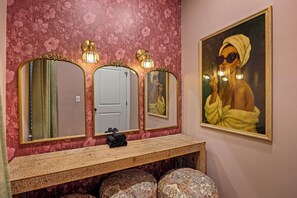 A bathroom with three mirrors, a vanity, and a framed painting on the wall.