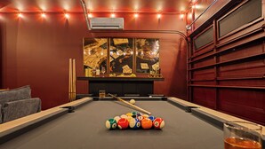 A pool table with balls, a glass of amber liquid, and a painting with playing cards. - New! Sleeps 20 — Hot Tub, Minigolf, Firepit,Outdoor Movie & Game Room (Charlotte)