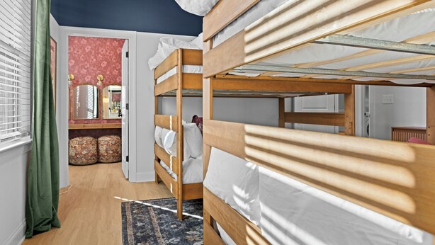 A bunk bed room with a window, a mirror, and a patterned rug. - New! Sleeps 20 — Hot Tub, Minigolf, Firepit,Outdoor Movie & Game Room (Charlotte)