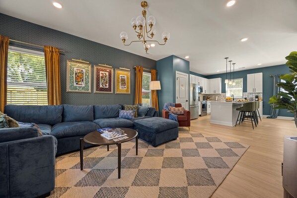 A modern living room with a sectional sofa, a coffee table, and a chandelier.