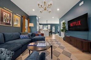 Ein modernes Wohnzimmer mit einer Couch, einem Couchtisch und einem Fernseher, der 'NETFLIX' zeigt.