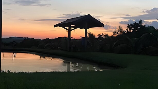 A gazebo structure near a body of water with a sunset in the background. - SHB Chácara para Eventos com Piscina (Elias Fausto)