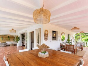 A spacious room with a wooden dining table, wicker ceiling lamps, and a view of lush greenery outside. - Villa Belle infinity pool and unique charm featuring 3 air-conditioned bedrooms (Grand-Bourg)