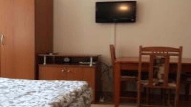 A bedroom with a bed, a wooden wardrobe, a desk with a chair, and a mounted television. - Studio in Cedar Lodge 3 (Bansko)