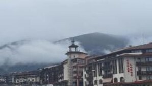 A mountainous landscape with a building featuring a tower and a sign with red characters. - Studio in Cedar Lodge 3 (Bansko)
