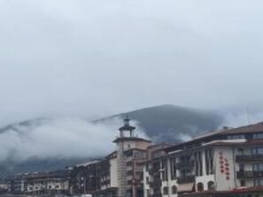 Paisagem montanhosa com um edifício que apresenta uma torre e uma placa com caracteres vermelhos.