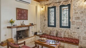 A cozy room with a stone wall, a fireplace, a chessboard, and a bench with pillows. - Aeriko Villa with Private pool - Where mountains meet the sea (Heraklion)