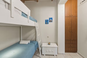 Ein Schlafraum mit Etagenbetten, einem weißen Nachttisch, einem Holzschrank und zwei Wandbildern.