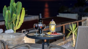 A table with a bottle, glasses, and fruit, set against a sunset view. - Aeriko Villa with Private pool - Where mountains meet the sea (Heraklion)