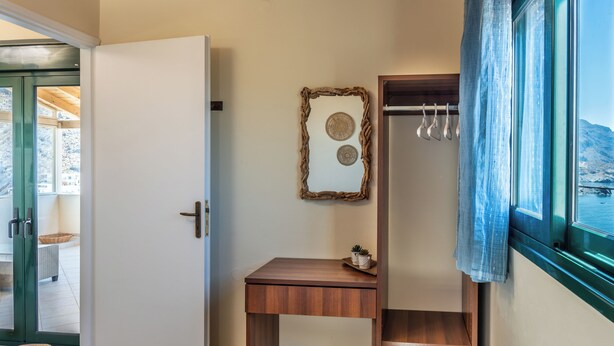 A room with a wooden bench, a small table, a door, and a window with a view of a mountain. - Aeriko Villa with Private pool - Where mountains meet the sea (Heraklion)