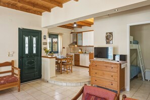 A compact kitchen with a dining area, wooden furniture, and a television. - Aeriko Villa with Private pool - Where mountains meet the sea (Heraklion)