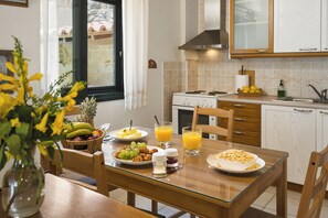 Eine moderne Küche mit Esstisch, gedeckt für ein Frühstück, inklusive Obst, Croissants und Müsli.