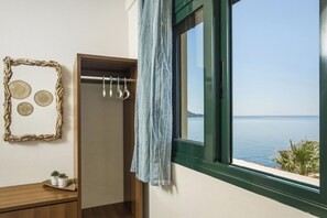 Ein Zimmer mit Holzschrank, Kleiderhaken und einem Fenster mit Meerblick, sowie einem an der Wand befestigten dekorativen Rahmen.