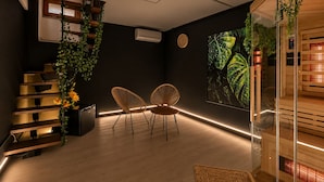 Ein modernes Interieur mit einer Treppe, zwei Sesseln, einer Wanduhr und einer großen Pflanze.