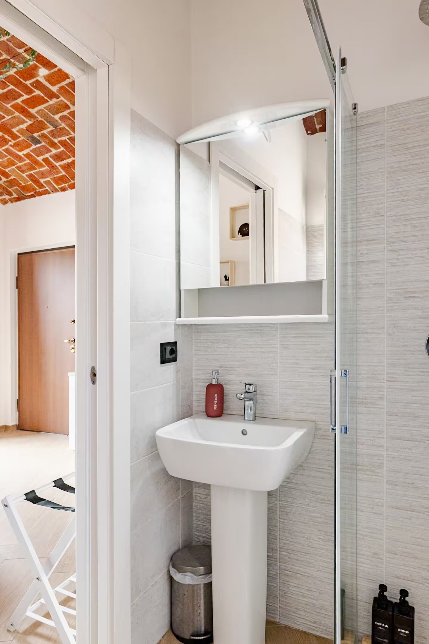Een badkamer met een wit wastafel, een spiegel en een douche.