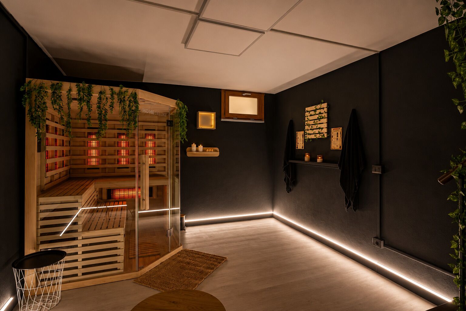 Ein modernes Interieur mit dunkler Wand, Holzboden, einer Glastrennwand und einem kleinen Holztisch.