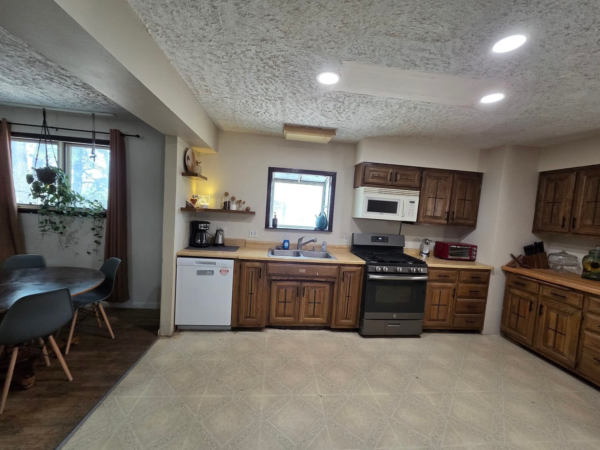 A compact kitchen with wooden cabinets, a built-in microwave, a stove, and a dishwasher.