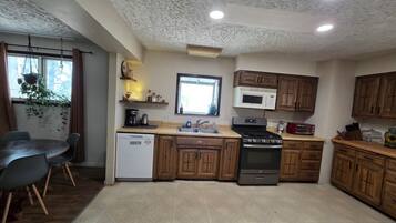 A compact kitchen with wooden cabinets, a built-in microwave, a stove, and a dishwasher.