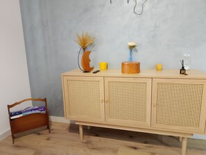 A wooden cabinet with perforated doors, a vase with dried plants, a small yellow cup, and a candle holder.