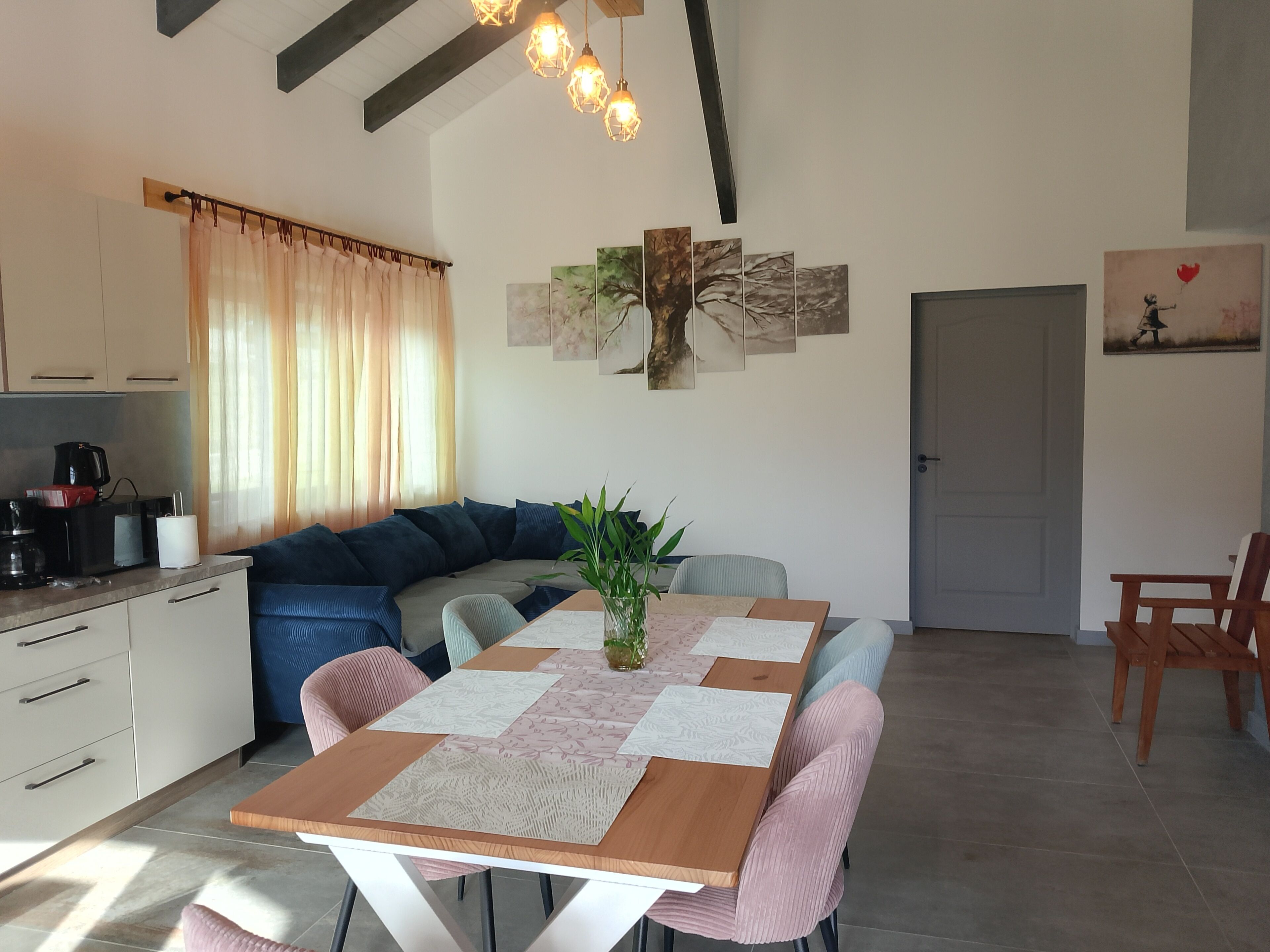Eine moderne Küche mit Essbereich, ausgestattet mit einem Holztisch, Stühlen und einer Couch.