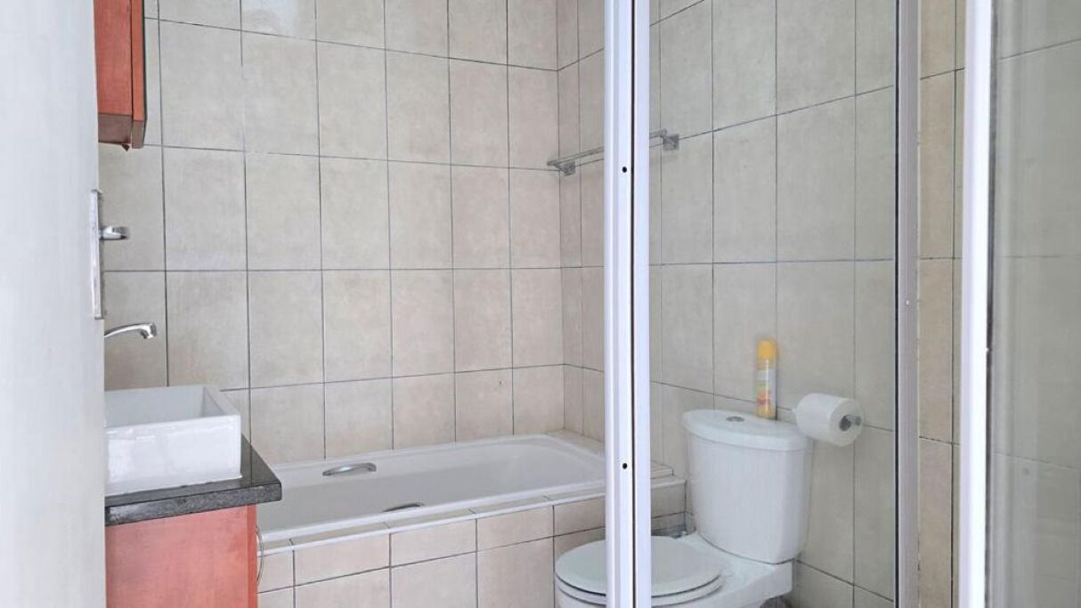 A bathroom with a bathtub, toilet, and a shower area.