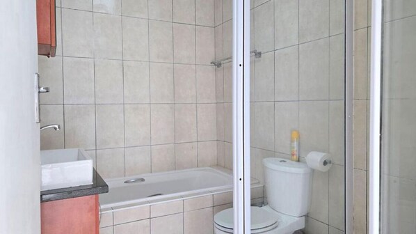 Un baño con bañera, inodoro y zona de ducha.