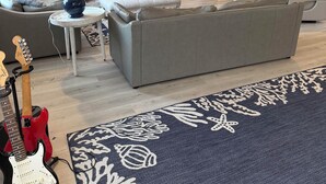 Ett modernt vardagsrum med en grå soffa, en tv och en röd elgitarr.