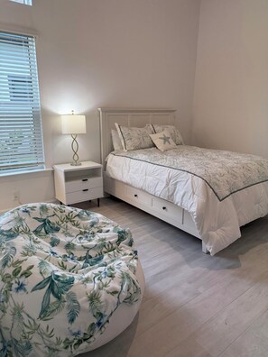 A bedroom with a bed, bedside table, lamp, and a round bean bag chair. - Newly built 4-bed house in Esplanade by the Islands BOAT INCLUDED with captain. (Naples)