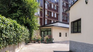 Ein Innenhof mit einem gepflasterten Weg, Kübelpflanzen und einem Gebäude mit Glastür.