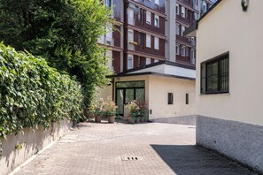 A courtyard with a paved walkway, potted plants, and a building with a glass door entrance. - [5 min from the M1 subway] Private Suite - CityLife (Milano)