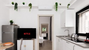 Eine moderne Küche mit integriertem Fernseher, der 'NETFLIX' anzeigt, einem Edelstahl-Kühlschrank und weißen Schränken.