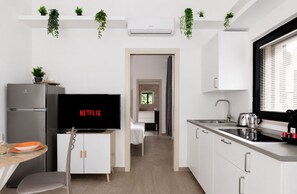 A modern kitchen with a built-in TV displaying 'NETFLIX,' a stainless steel refrigerator, and white cabinetry. - [5 min from the M1 subway] Private Suite - CityLife (Milano)