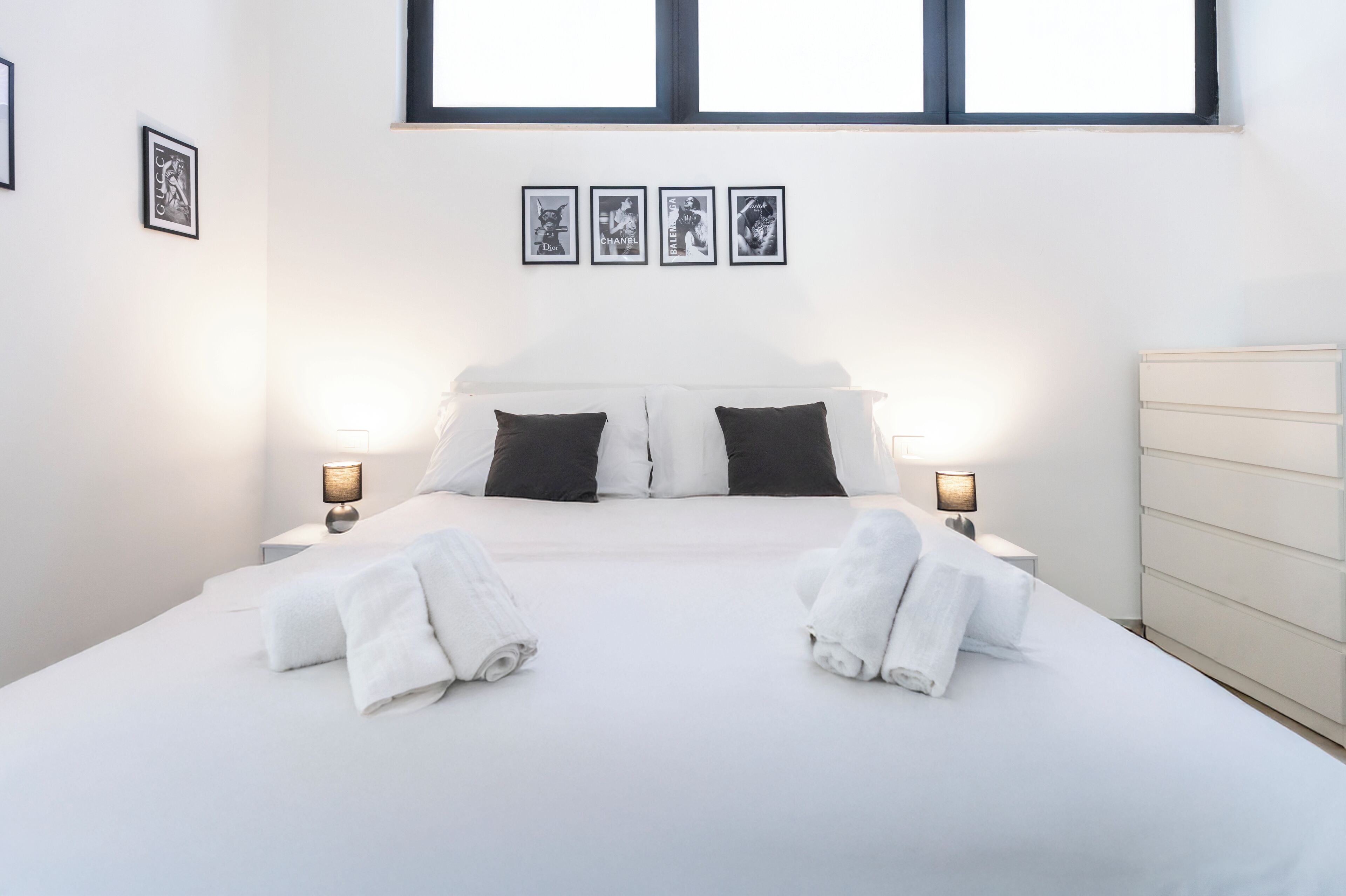 Ein Hotelzimmer mit einem großen Bett, zwei Kissen, zwei Nachttischlampen und einem Schminktisch.