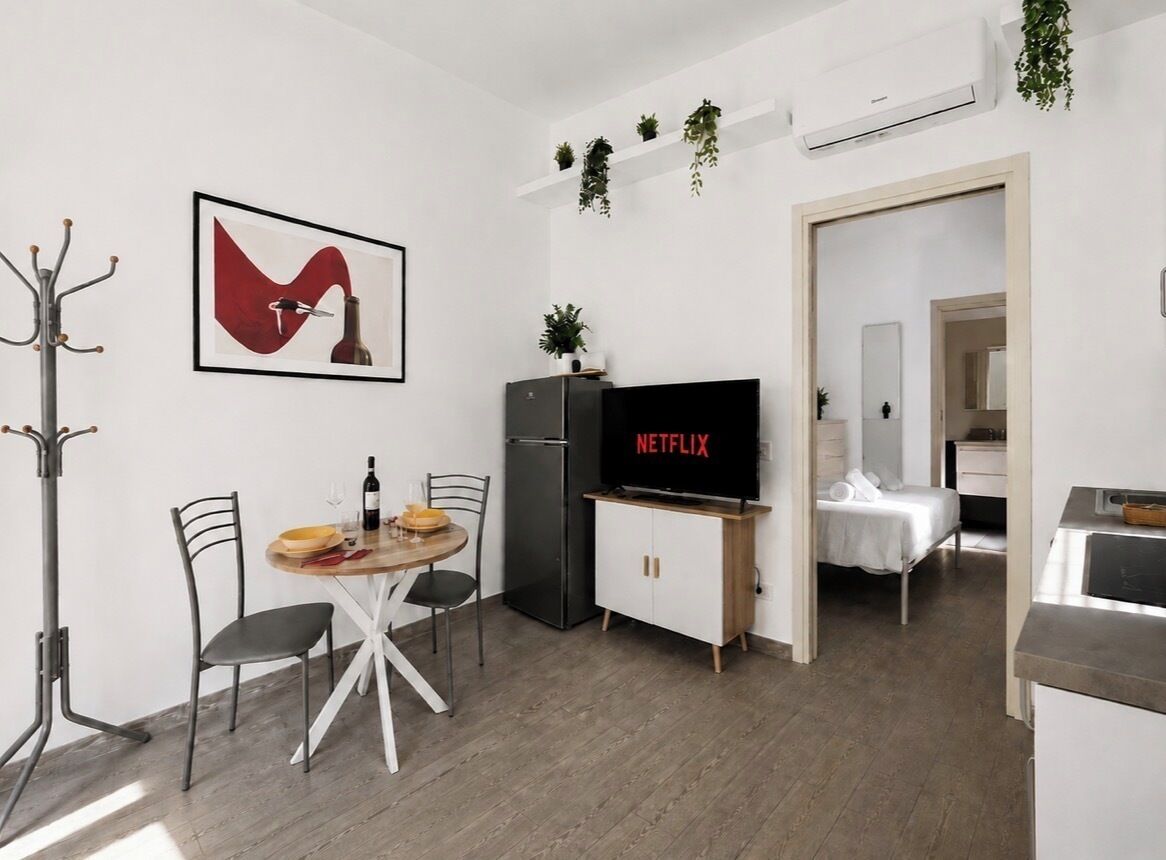 Un espace de vie compact comprenant un coin repas, une kitchenette, un téléviseur diffusant du contenu « NETFLIX » et un petit coin salon.