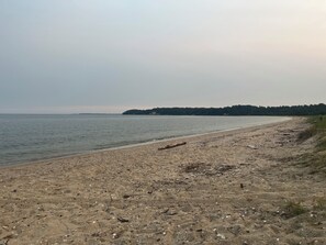 A beach with a sandy shore and a forested island in the distance. - 3-bedroom house in beautiful Cove point Beach! Just a short walk from the beach (Lusby)