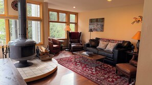 A cozy living room with a wood-burning stove, leather furniture, and large windows. - "Frisco Mountain Retreat 3BR/3BA, Sleeps 7 — Steps from Slopes & Summer Trails" (Frisco)