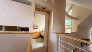A staircase with a wooden handrail leading to a bedroom with a bed, a nightstand, and a lamp. - "Frisco Mountain Retreat 3BR/3BA, Sleeps 7 — Steps from Slopes & Summer Trails" (Frisco)