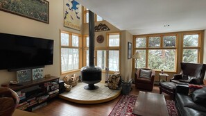A cozy living room with a fireplace, large windows, and a television. - "Frisco Mountain Retreat 3BR/3BA, Sleeps 7 — Steps from Slopes & Summer Trails" (Frisco)