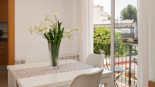 A dining area with a table, chairs, a vase with flowers, and a view of the outside. - Beautiful, centrally located apartment (Sitges)