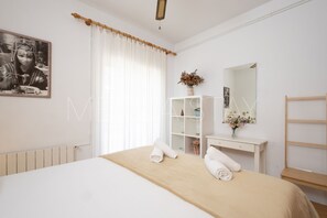 A bedroom with a bed, a white dresser, a mirror, and a window with curtains. - Beautiful, centrally located apartment (Sitges)