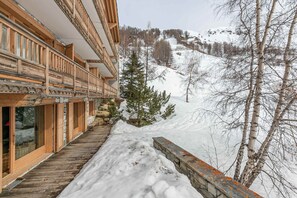 Un bâtiment en bois doté de balcons, un sentier pavé de pierres et une montagne enneigée en arrière-plan.