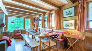 Ein rustikales Holzinterieur mit einem langen Esstisch, Bänken und einer Sitzgruppe.